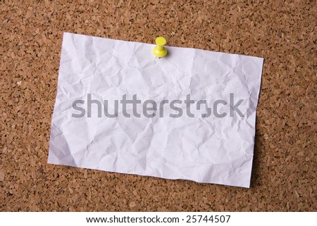 A crumpled paper stuck to a cork noticeboard