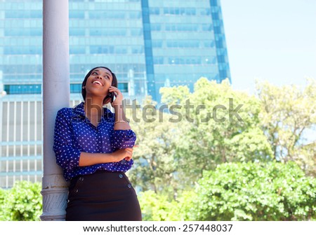 Young business woman laughing on cell phone outside office building