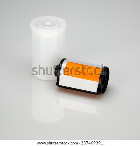 35 mm camera film is lying near jar, isolated on white background