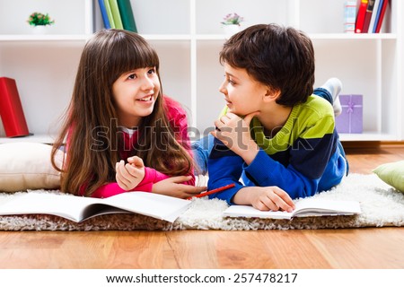 Little girl and little boy have decided to take a break from homework and now they are having conversation.Children talking Royalty-Free Stock Photo #257478217