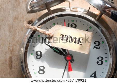 Time concept, retro alarm clock on  a wooden table and label "time".
