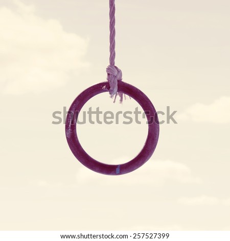 The concept of loneliness-a wooden ring hangs on a sky background.Special toned photo in vintage style