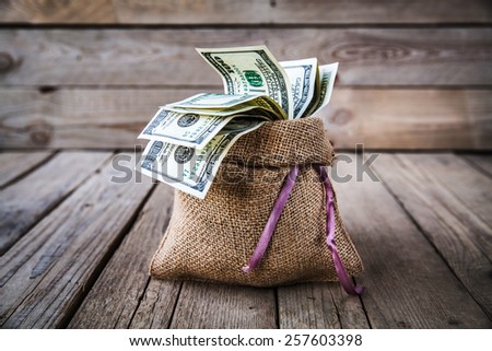 backwards money in burlap sack on wooden background