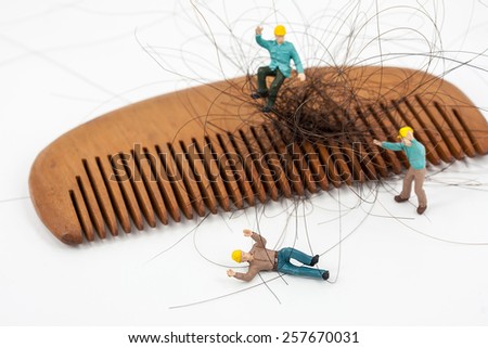 selective focus photo of miniature workers lay down on floor with wooden comb, abstract background to solution hair loss concept.
