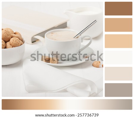 Amaretti Biscuits. Cup Of Cappuccino Coffee. Lump Demerara Sugar. Book With Handmade Textile Cover. Palette With Complimentary Colour Swatches.