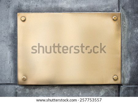 blank gold or brass metal sign or nameboard on concrete wall