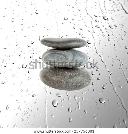 Three grey pebble stones over water drops  background