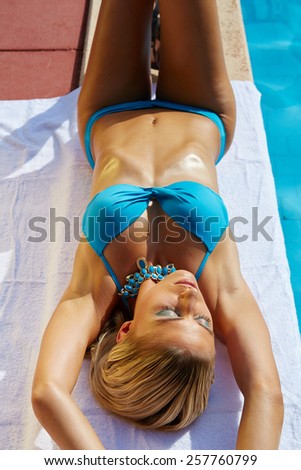 a young woman sunbathing near swimming pool.
