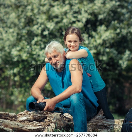 Grandfather with his granddaughter travel at attractive places. Old man photographer on a camping trip with his granddaughter.
