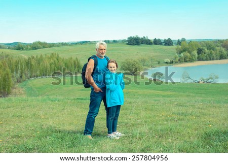 Portrait of grandfather and granddaughter in a landscape of open space Old man photographer on a camping trip with his granddaughter.