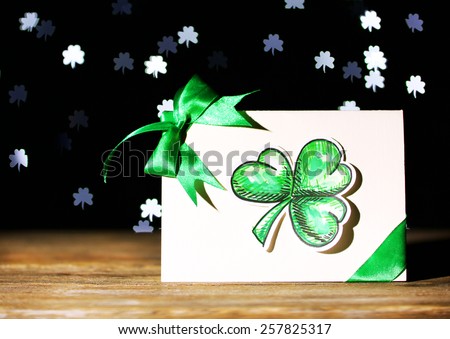 Greeting card for Saint Patrick's Day on wooden table on dark lights background