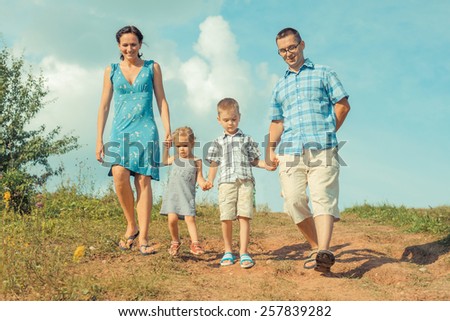 young happy family of four down from the mountains in the background of clouds