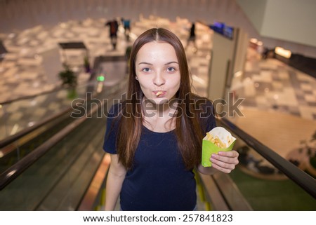 Young girl eating fast food in a shopping mall