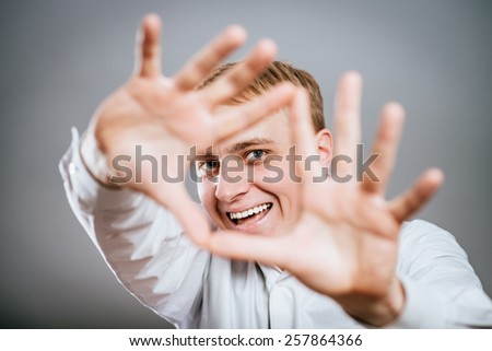 smiling attractive young man makes the heart using fingers