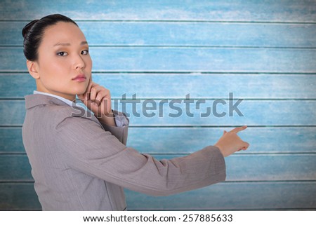 Thoughtful asian businesswoman pointing against wooden planks
