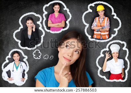 Education and career choice options - student thinking of future. Young Asian woman contemplating career options smiling looking up at thought bubbles on a blackboard with different professions Royalty-Free Stock Photo #257886503