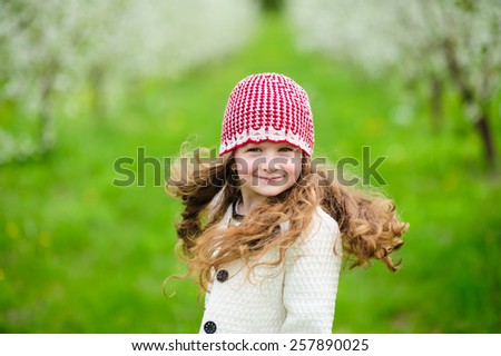 Portrait of Little pretty girl in the green blooming garden 
