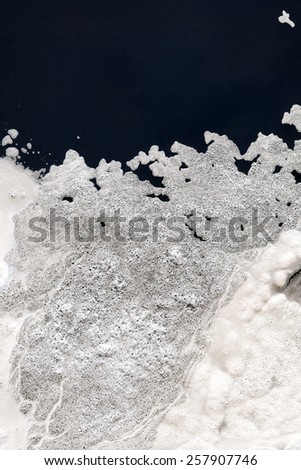 White foam with open patches of water, vertical image.