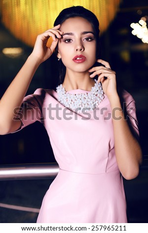 fashion photo of beautiful young woman with dark hair wearing elegant dress posing  in interior