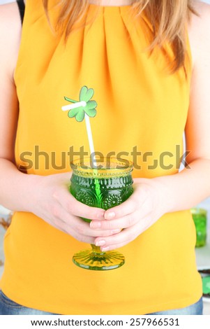 Woman holding glass of drink with clover leaf for St Patrick Day close up