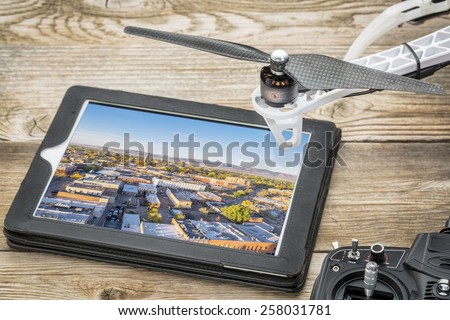 drone aerial photography concept - reviewing aerial pictures of Fort Collins downtown on a digital tablet with a drone rotor and radio control transmitter,