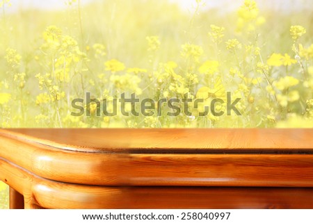 wood board table in front of summer landscape with double exposure of flower field bloom
