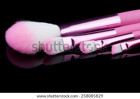 pink make-up brushes isolated on black background.