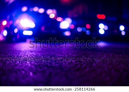 Nights lights of the big city, close up view from asphalt level on the lights of cars. Image in the red-blue toning