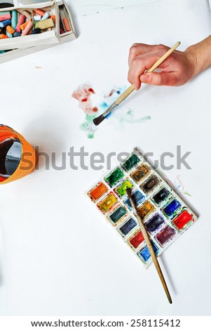 The artist's hand drawing a water color on paper. Art background