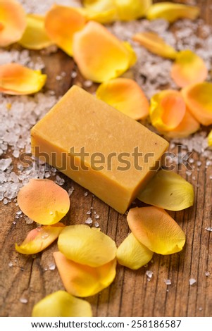 roses petals with soap and pile salt on old wooden board