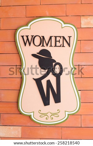 Modern sign on the brick wall of toilet. Text "women"