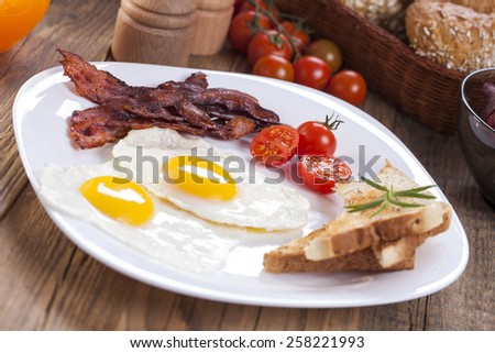 Fried egg and bacon on a plate with spices and vegetables. studio picture