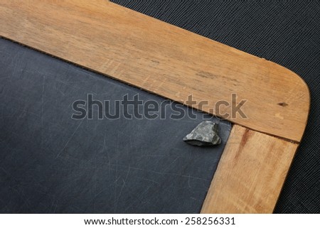 Vintage and old slate blackboard and stone put on the black color leather background represent the teaching equipment related.