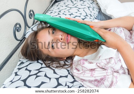 young beautiful girl lying in bed feeling sick with teeth ache