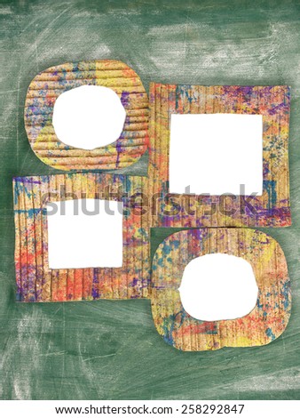 Group of blank colorful painted cardboard frames on grunge chalkboard 