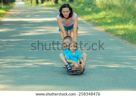 Family fun with skateboard. Mom rolls young children on a skateboard