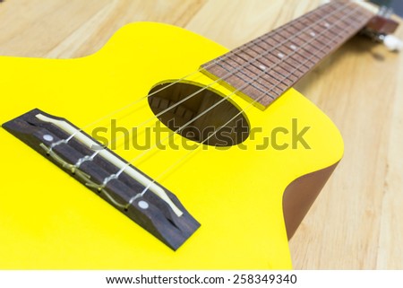 Yellow ukulele guitar on a wooden table