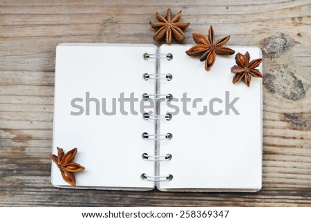 An empty retro spiral notebook with old paper and anise stars on wooden table