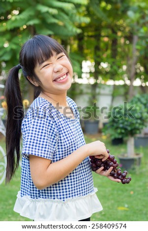 Asian girl smiling with grapes.