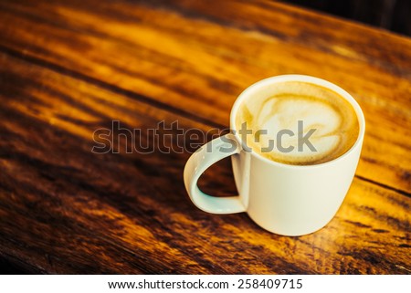 Hot latte cup on wooden background - vintage effect style pictures