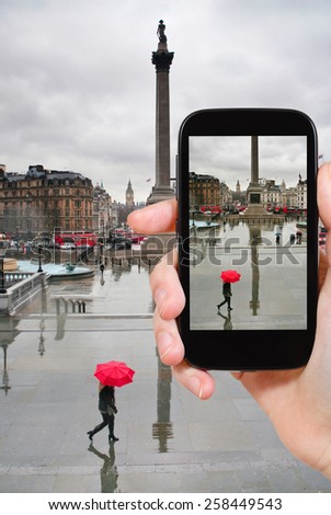 travel concept - tourist taking photo of trafalgar square in London on mobile gadget, England