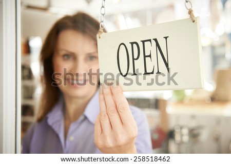 Store Owner Turning Open Sign In Shop Doorway Royalty-Free Stock Photo #258518462