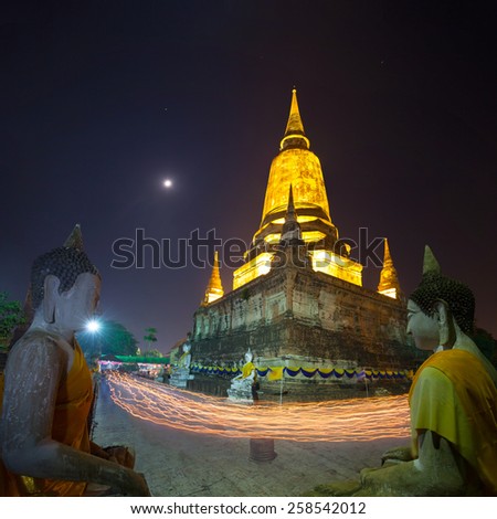 People hold candle light walking pass the front of pagoda in wian tian ceremony. part of Magha Puja the ruin of Wat Yai Chai Mongkol in Ayutthaya