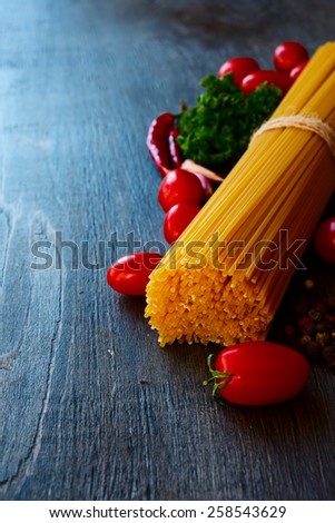 Spaghetti and tomatoes with herbs on wooden texture. Selective focus.
