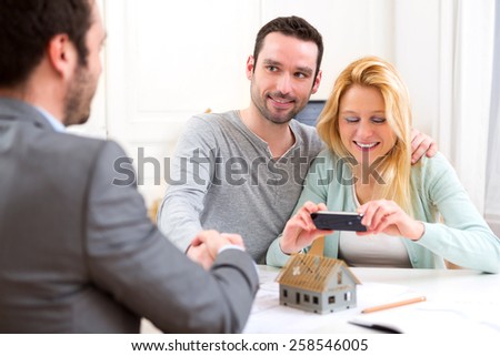 View of Young man handshaking real estate while his wife take picture