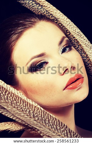 Beautiful woman with brown professional make-up with feathers.