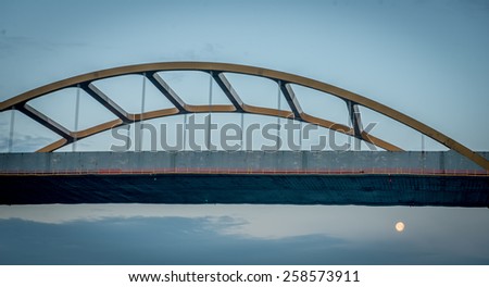 Bridge at sunrise with a fulll moon just beneath it in Milwaukee, WI