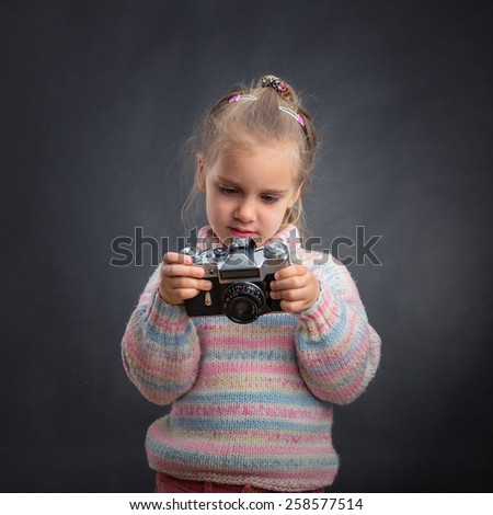 Little cute girl looks photos at the camera