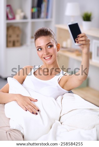 Happy woman taking a photo of herself with her mobile phone in a bedroom