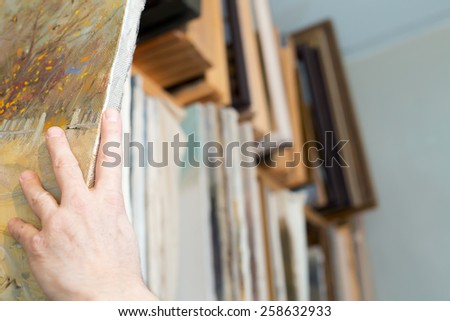 An artist taking canvas from shelving
